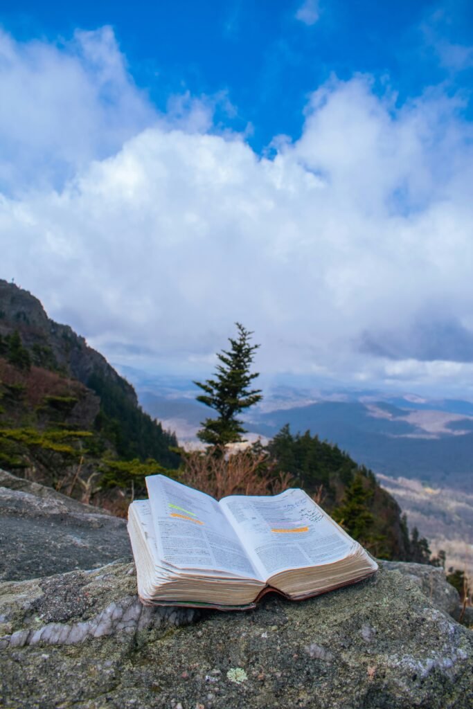Open Bible resting on a rock overlooking mountains