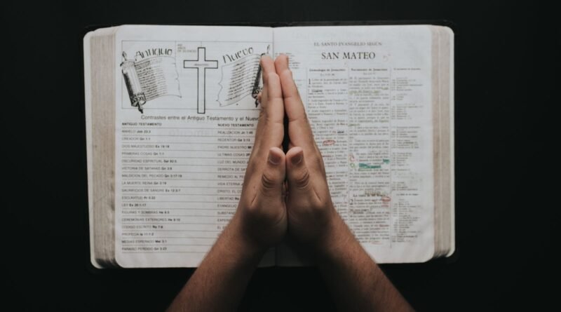 Hands folded in prayer over an open Bible (photo: Pexels)
